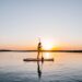 a paddleboarder on the sea during sunset